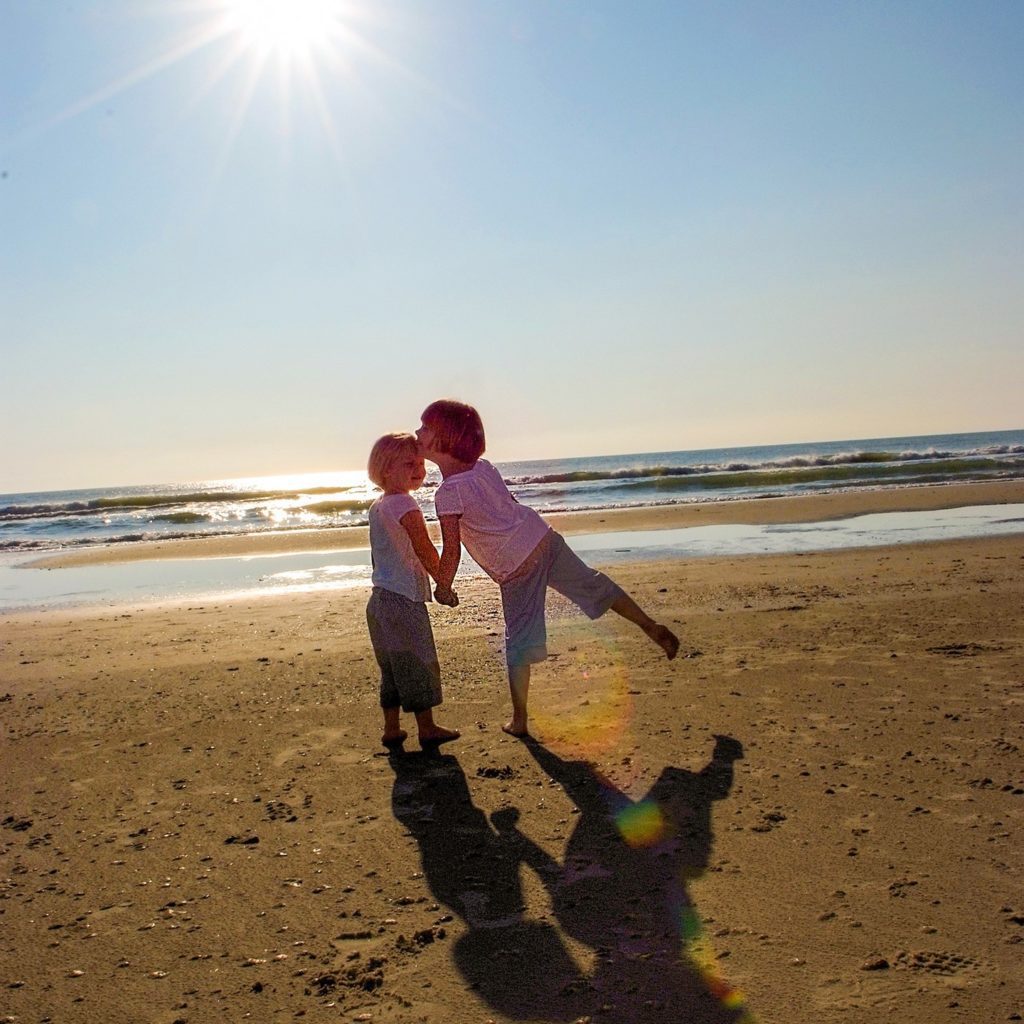 Corolla family photographer interacting with young children during beach portrait session