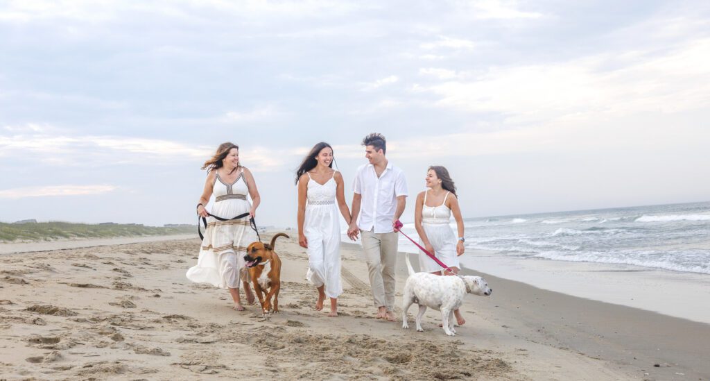 Family with dog walking along Corolla beach at sunset Outer Banks NC