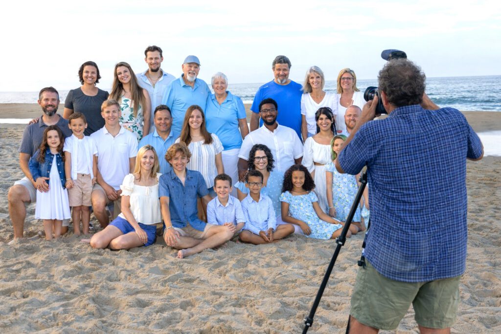 Professional photographer organizing large family group portrait on Corolla beach